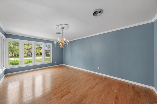 empty room featuring a chandelier, baseboards, visible vents, and crown molding