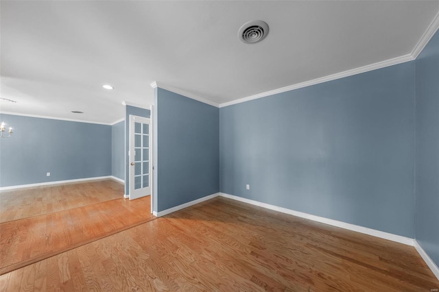 unfurnished room featuring a notable chandelier, wood finished floors, ornamental molding, and baseboards