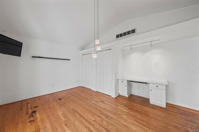 unfurnished bedroom featuring track lighting, visible vents, light wood finished floors, and lofted ceiling