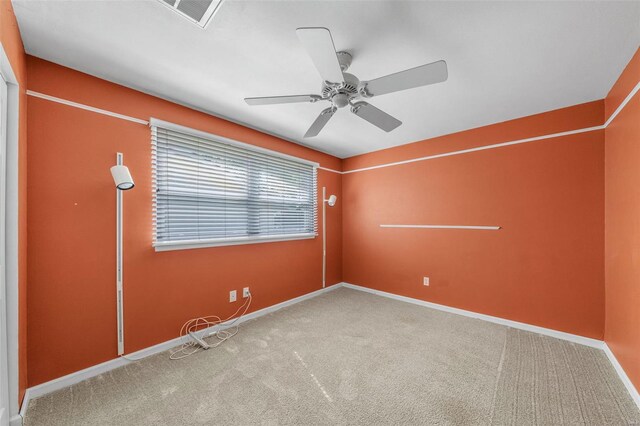 empty room with visible vents, a ceiling fan, carpet flooring, and baseboards