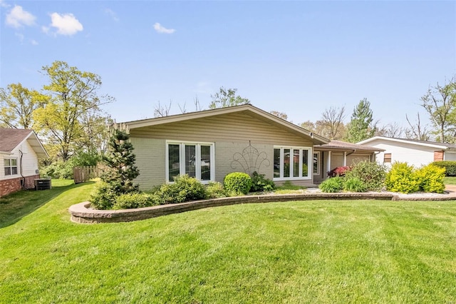 rear view of house with a yard, central AC unit, and brick siding