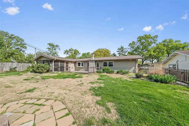 rear view of property with a sunroom, a wooden deck, a yard, and a fenced backyard