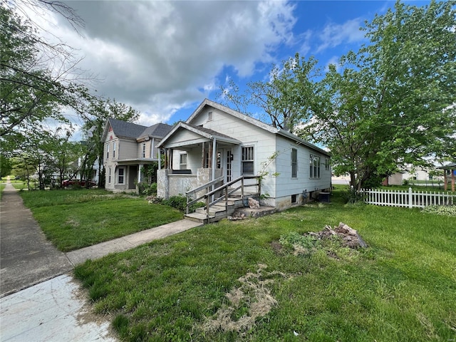 bungalow featuring fence and a front lawn