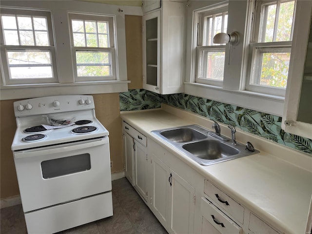 kitchen featuring electric stove, a sink, white cabinetry, and light countertops