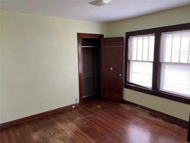 unfurnished bedroom with baseboards, a closet, and dark wood finished floors