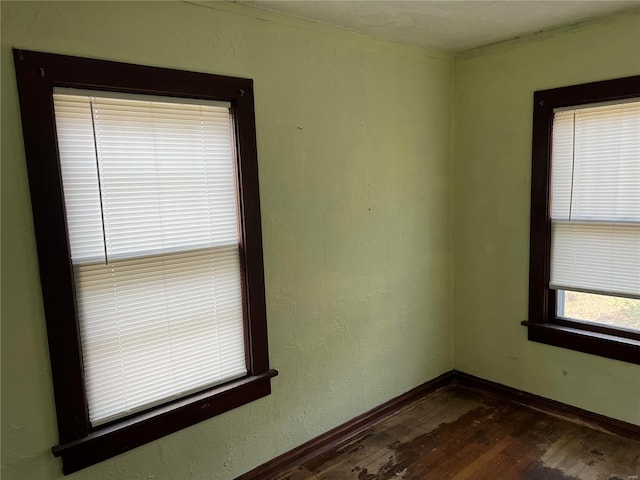 empty room featuring baseboards and dark wood-type flooring