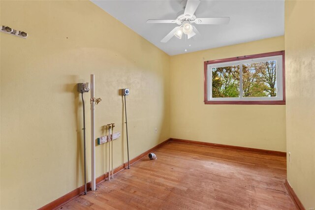 spare room featuring light wood-style flooring, baseboards, and a ceiling fan