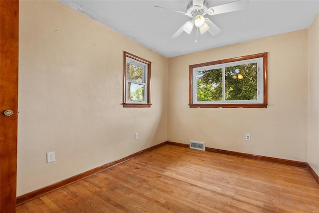 empty room featuring baseboards, a ceiling fan, visible vents, and light wood-style flooring