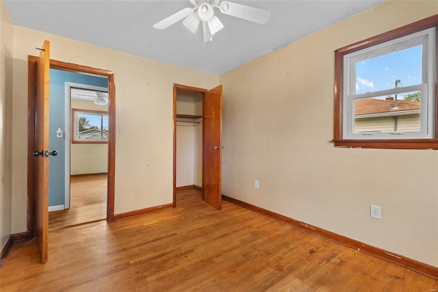 unfurnished bedroom with light wood-type flooring, a closet, a ceiling fan, and baseboards