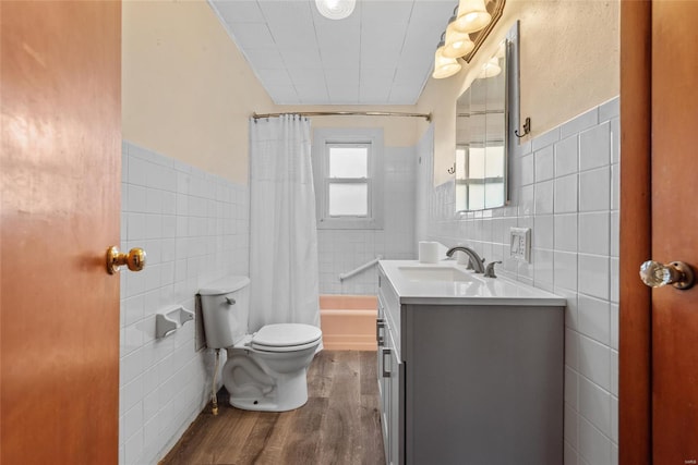 bathroom featuring wood finished floors, vanity, shower / bathtub combination with curtain, tile walls, and toilet