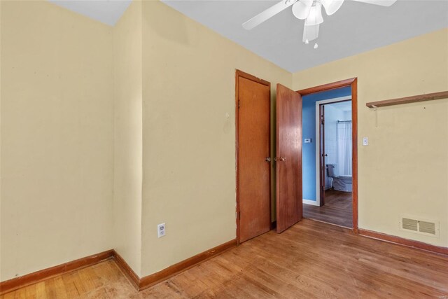 spare room featuring baseboards, a ceiling fan, visible vents, and light wood-style flooring