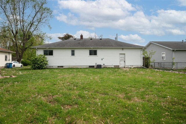 back of property featuring fence, a chimney, a yard, and central air condition unit