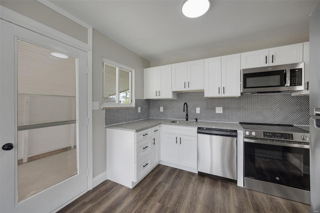 kitchen with a sink, dark wood-type flooring, tasteful backsplash, appliances with stainless steel finishes, and white cabinetry