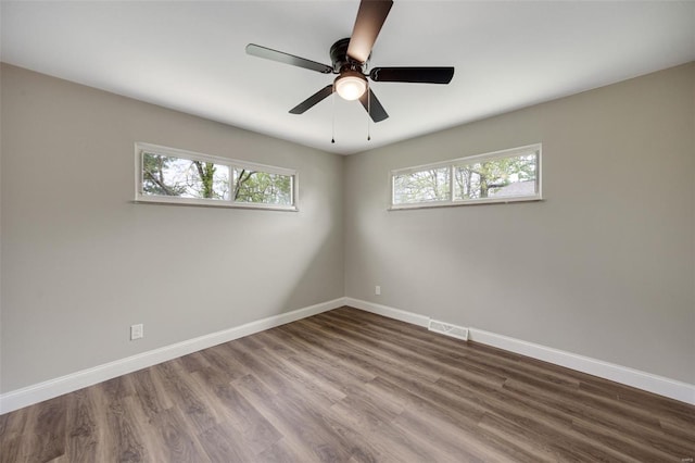 empty room featuring visible vents, baseboards, ceiling fan, and dark wood-style flooring