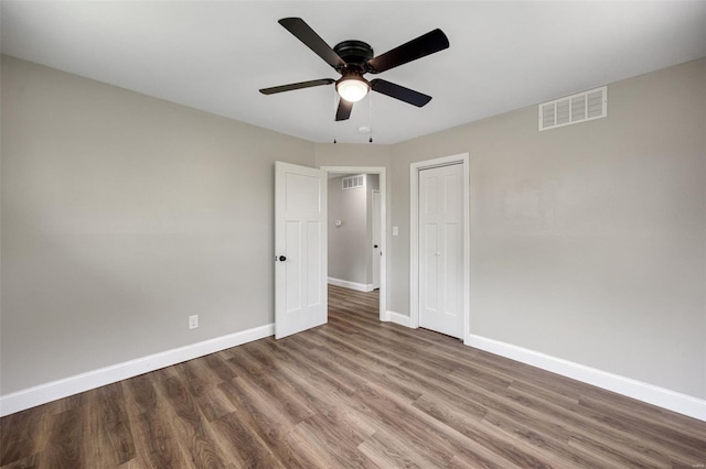 unfurnished bedroom featuring baseboards, wood finished floors, visible vents, and a closet