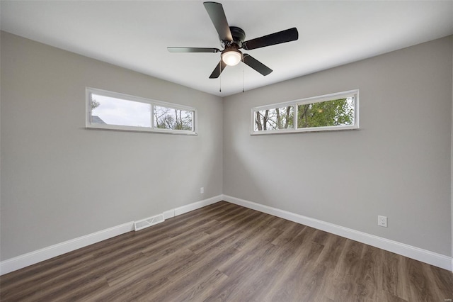 empty room with visible vents, wood finished floors, baseboards, and ceiling fan
