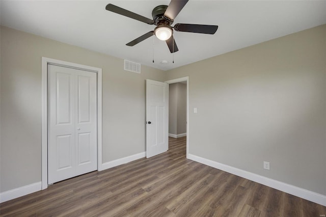 unfurnished bedroom with a closet, wood finished floors, visible vents, and baseboards