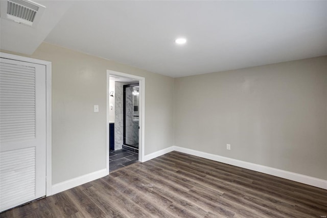 empty room with dark wood-type flooring, visible vents, baseboards, and recessed lighting