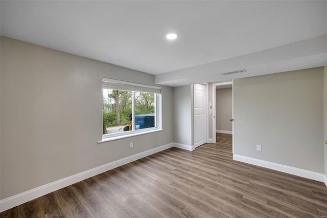 unfurnished room with visible vents, wood finished floors, baseboards, and recessed lighting
