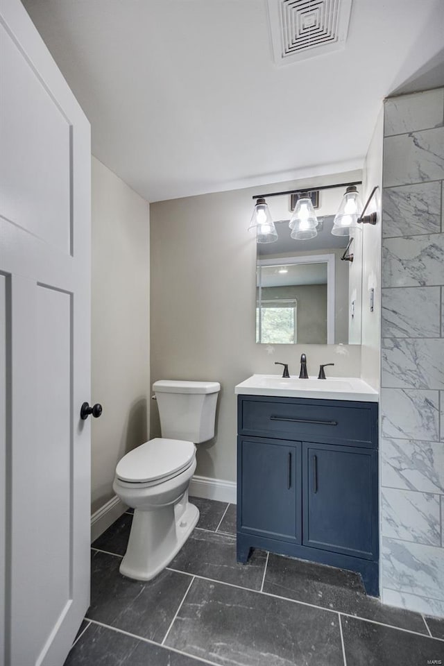 bathroom featuring toilet, vanity, visible vents, and baseboards