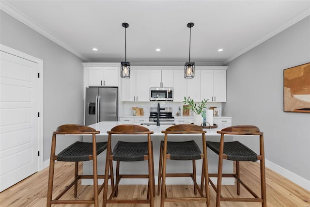 kitchen with a kitchen breakfast bar, a kitchen island with sink, backsplash, crown molding, and appliances with stainless steel finishes