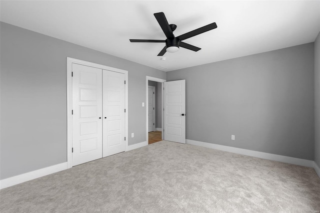unfurnished bedroom with carpet flooring, baseboards, ceiling fan, and a closet