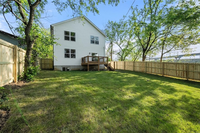 rear view of house with a fenced backyard, a wooden deck, a yard, and stairway