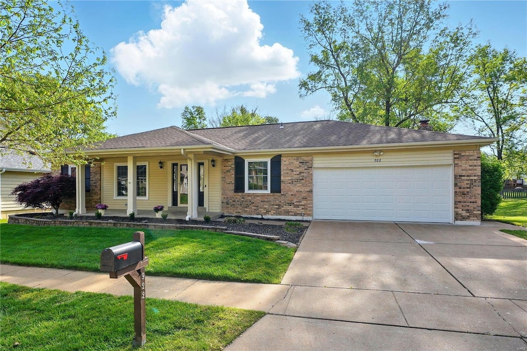 ranch-style home with brick siding, an attached garage, a front lawn, and concrete driveway