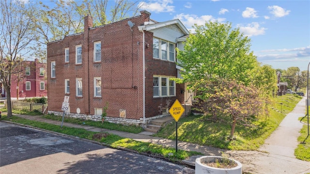 view of home's exterior featuring fence, a chimney, and brick siding
