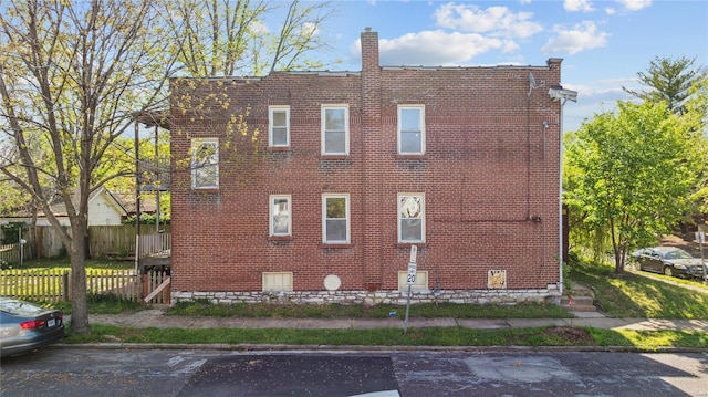 view of side of property with brick siding and fence