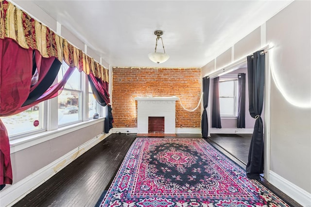 unfurnished living room featuring baseboards, hardwood / wood-style floors, a fireplace, and plenty of natural light