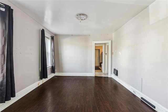 empty room featuring baseboards, visible vents, and wood finished floors
