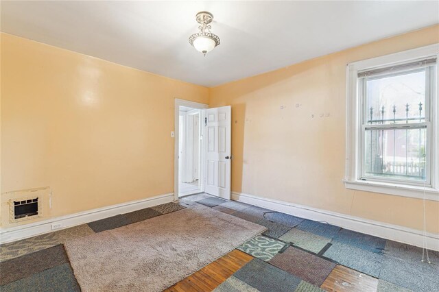 empty room with heating unit, wood finished floors, and baseboards