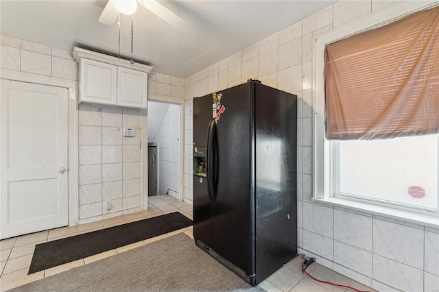 kitchen featuring light tile patterned floors, tile walls, a ceiling fan, and black fridge with ice dispenser