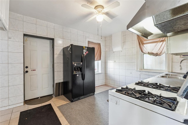 kitchen featuring tile walls, a sink, under cabinet range hood, and black fridge with ice dispenser