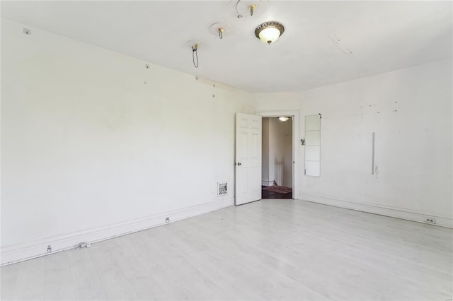 empty room with wood finished floors, visible vents, and baseboards