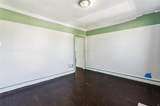 empty room featuring visible vents, wood finished floors, and baseboards