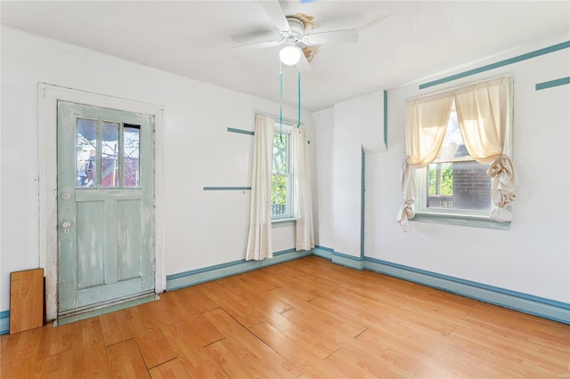 spare room with baseboards, a ceiling fan, and light wood finished floors