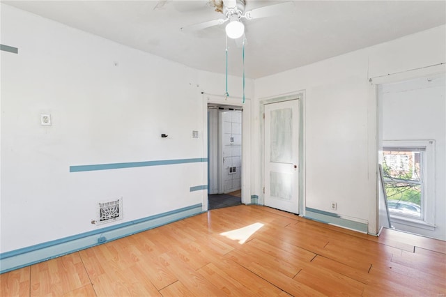 spare room with a baseboard heating unit, ceiling fan, wood finished floors, and baseboards