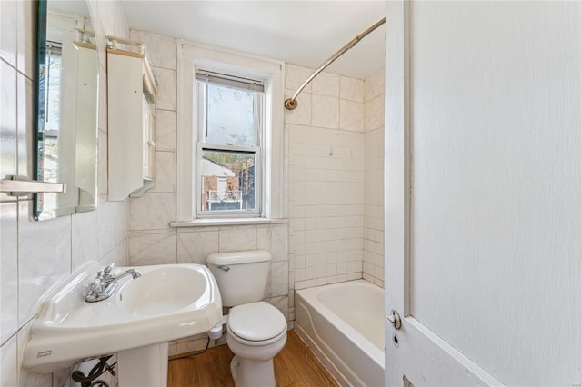 full bath with a sink, tub / shower combination, toilet, tile walls, and wood finished floors