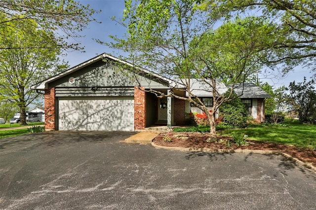 view of front of house with brick siding, a front lawn, driveway, and a garage