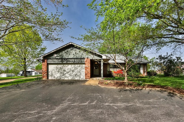 view of front of house with a garage, driveway, a front lawn, and brick siding