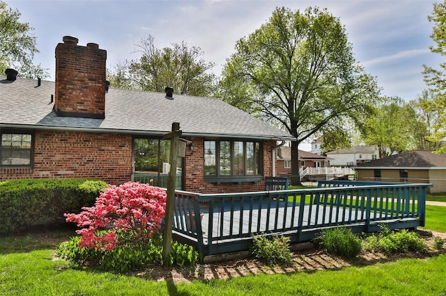rear view of house featuring a chimney, brick siding, and a deck