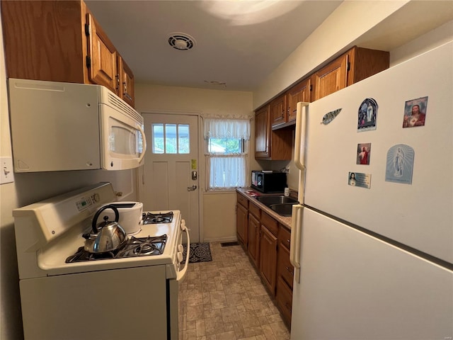 kitchen with a sink, brown cabinetry, white appliances, and visible vents