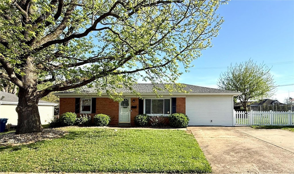 ranch-style house featuring brick siding, a front lawn, fence, and concrete driveway