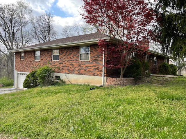 view of side of property with brick siding, a yard, and a garage