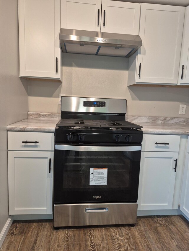 kitchen with white cabinets, under cabinet range hood, light countertops, dark wood-type flooring, and stainless steel range with gas cooktop