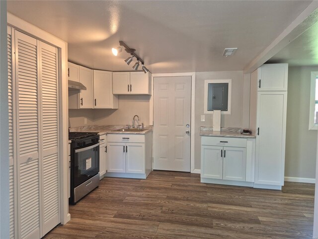 kitchen with a sink, under cabinet range hood, stainless steel gas stove, white cabinets, and dark wood-style flooring