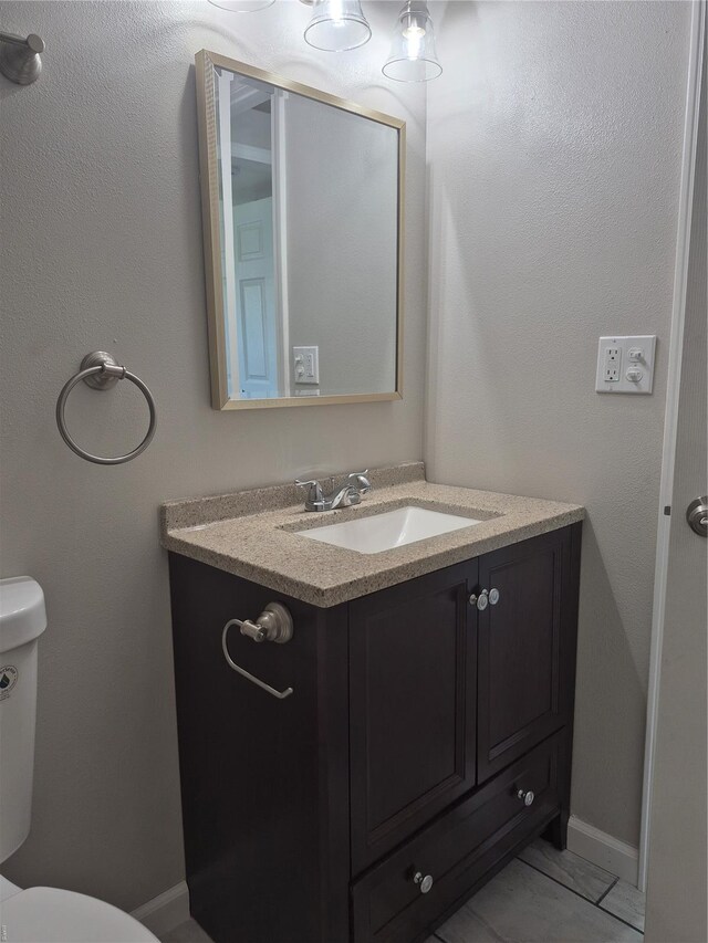 bathroom featuring baseboards, vanity, and toilet