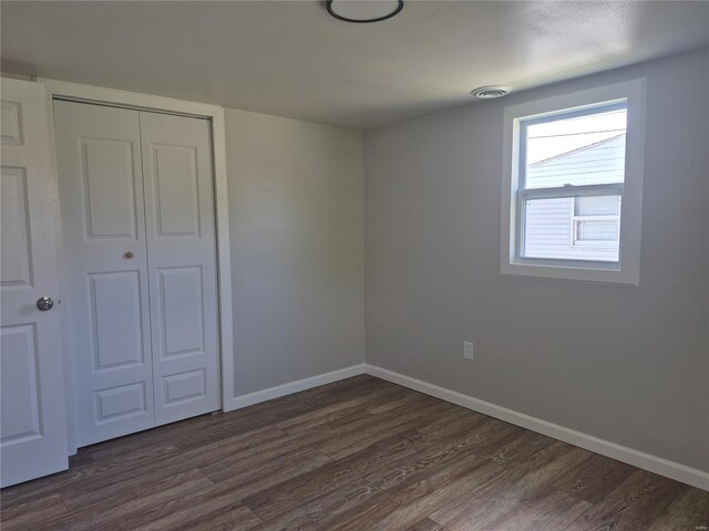 unfurnished bedroom with visible vents, baseboards, dark wood-style floors, and a closet
